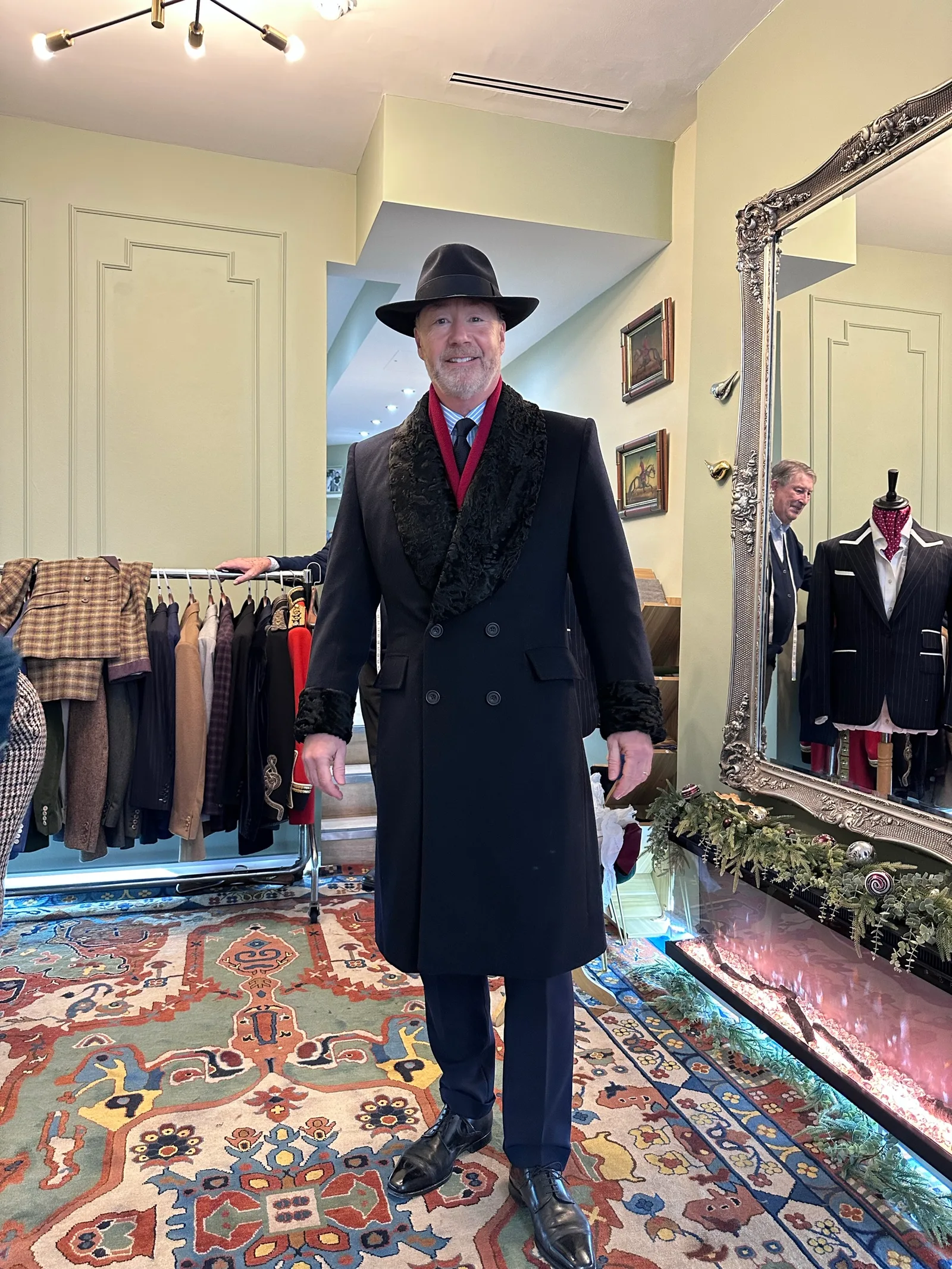 A wearer in a brimmed hat models the midnight cashmere evening coat in the salon.