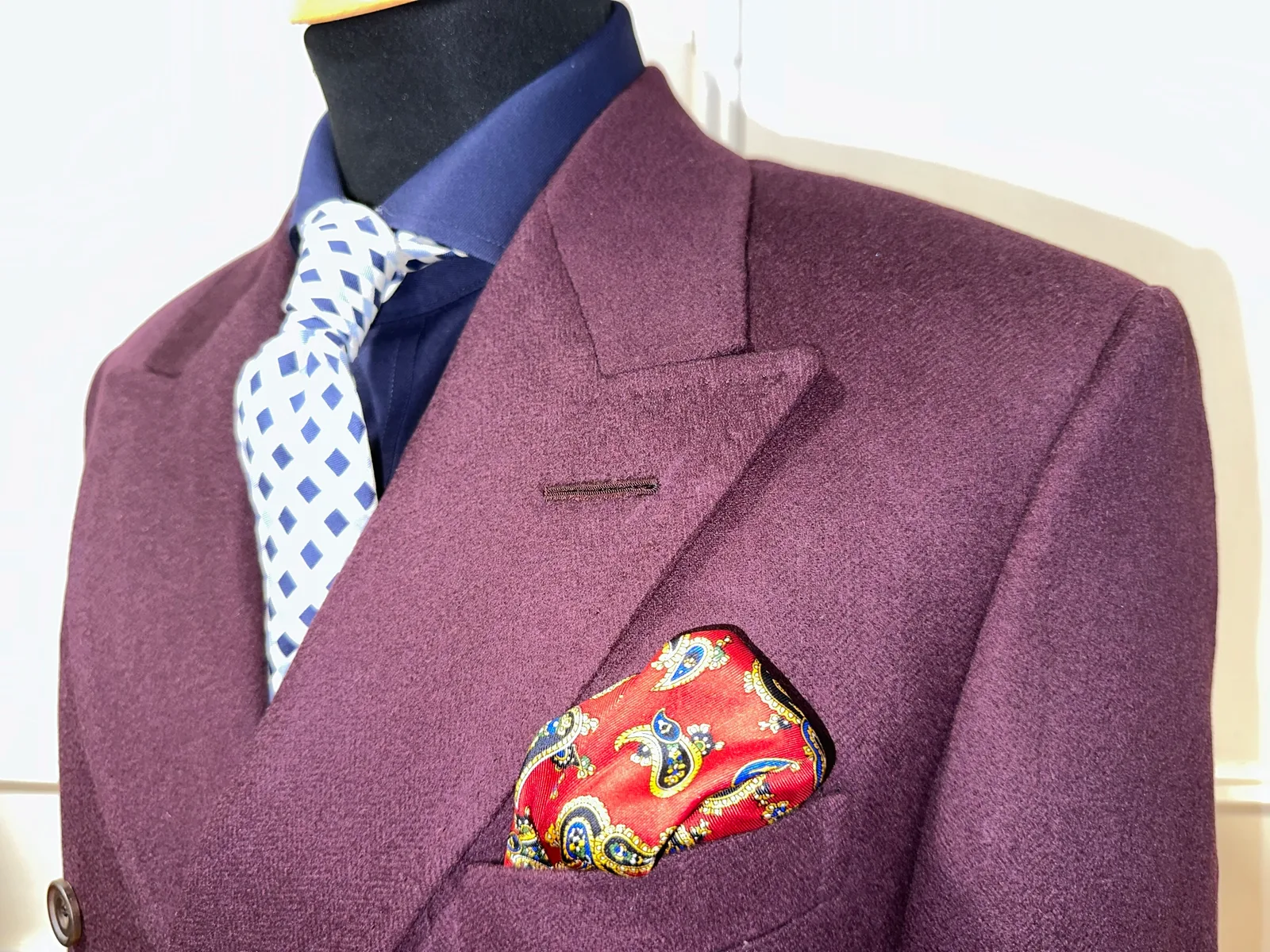 Close view of a deep mulberry double-breasted jacket, highlighting peak-lapel detail.