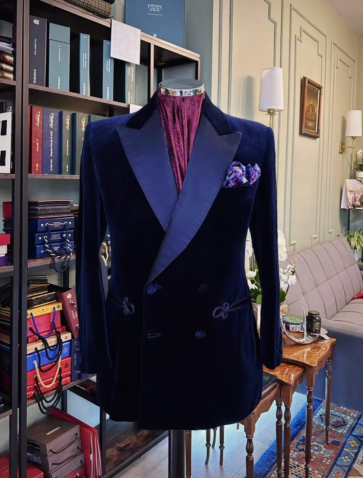 Full front view of a midnight velvet double-breasted evening jacket with frog closures on a tailor’s mannequin