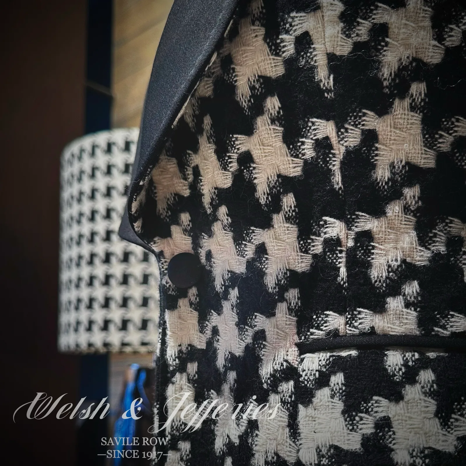 Pocket and cloth detail on black-and-ivory houndstooth ladies' jacket with a black shawl collar.