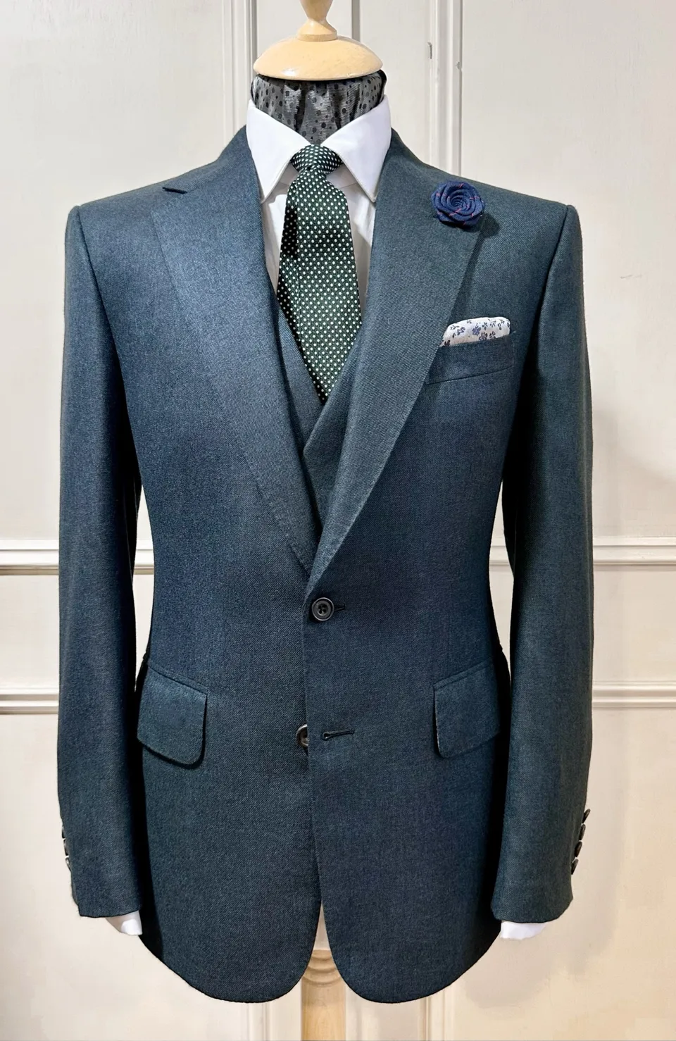 Petrol-blue three-piece suit with a sculpted waist and softly roped shoulders.