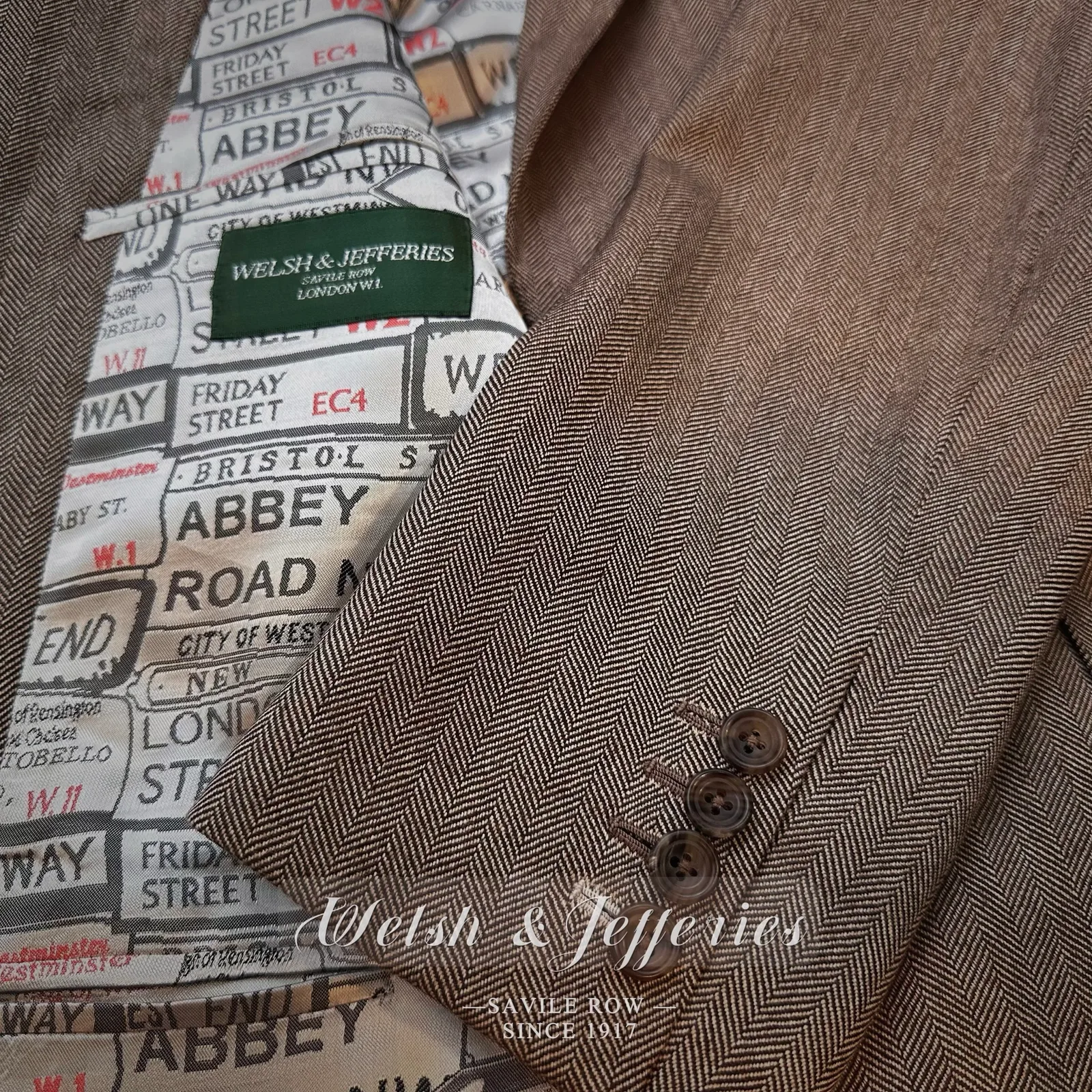 Close view of taupe herringbone, horn buttons, pocket finishing and map-print lining.