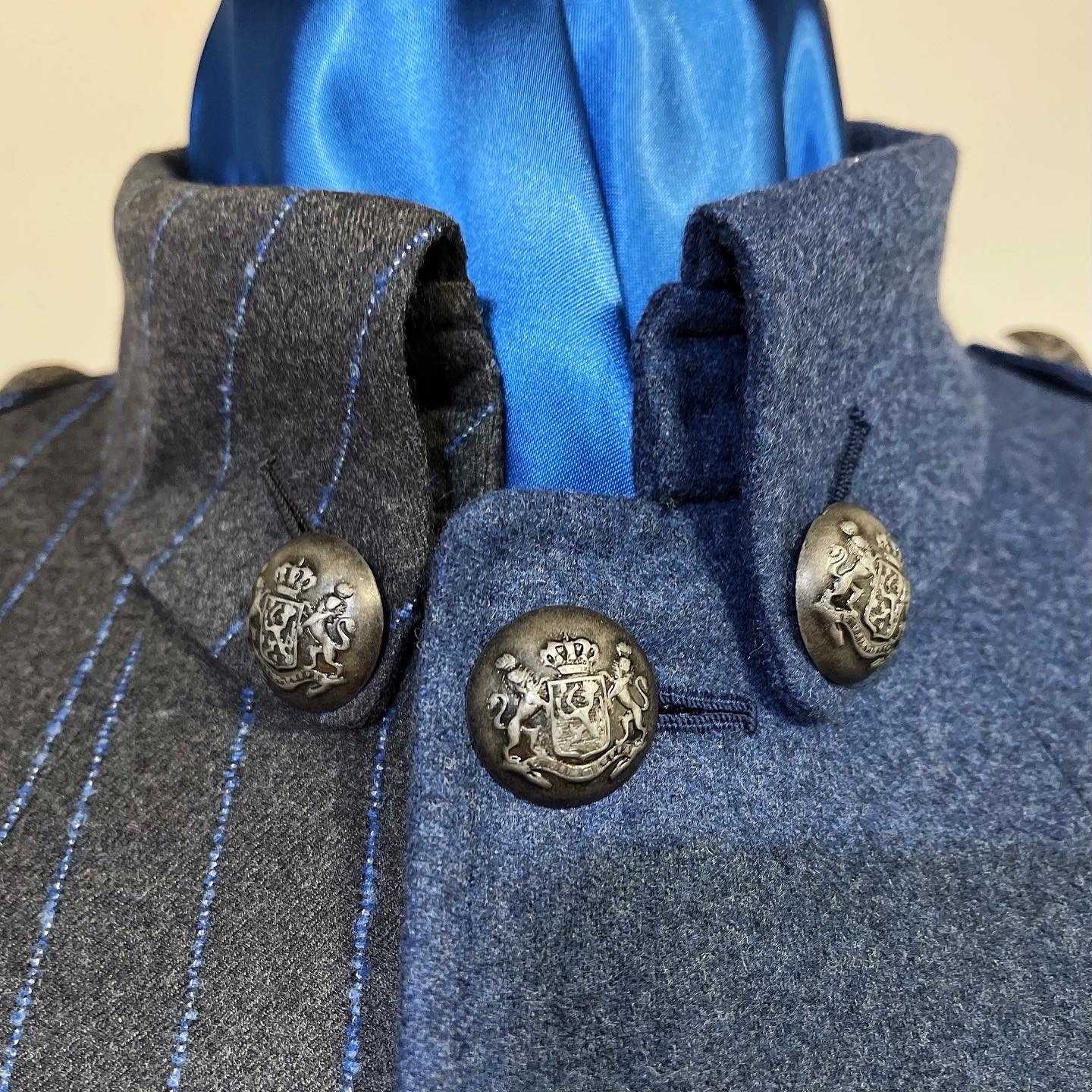 High split-cloth collar fastened by three crowned armorial metal buttons.