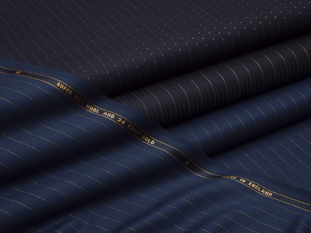 Bolts of midnight blue Scabal cloth reveal fine gold pinstripes and branded selvedges.