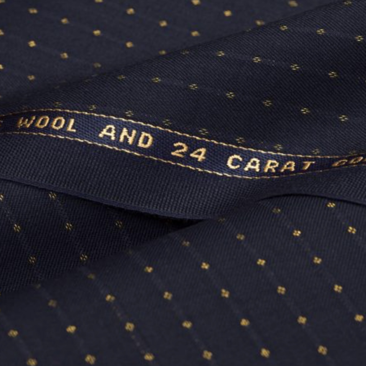A navy Scabal micro-diamond cloth folds across its 24-carat-gold selvedge.