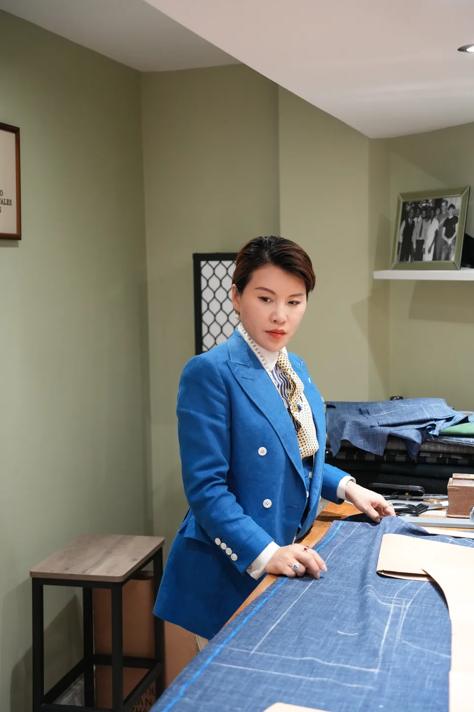 A cutter in cobalt tailoring stands poised beside chalked blue cloth.