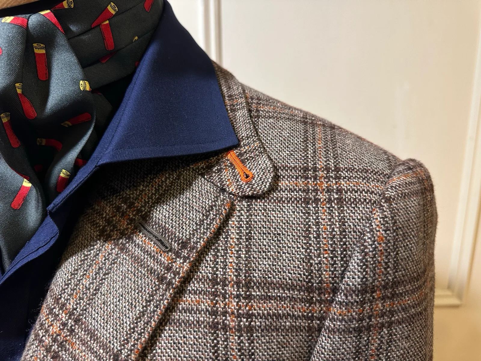 Close view of a brown Glen-check jacket with suede cuffs, highlighting lapel and collar detail.