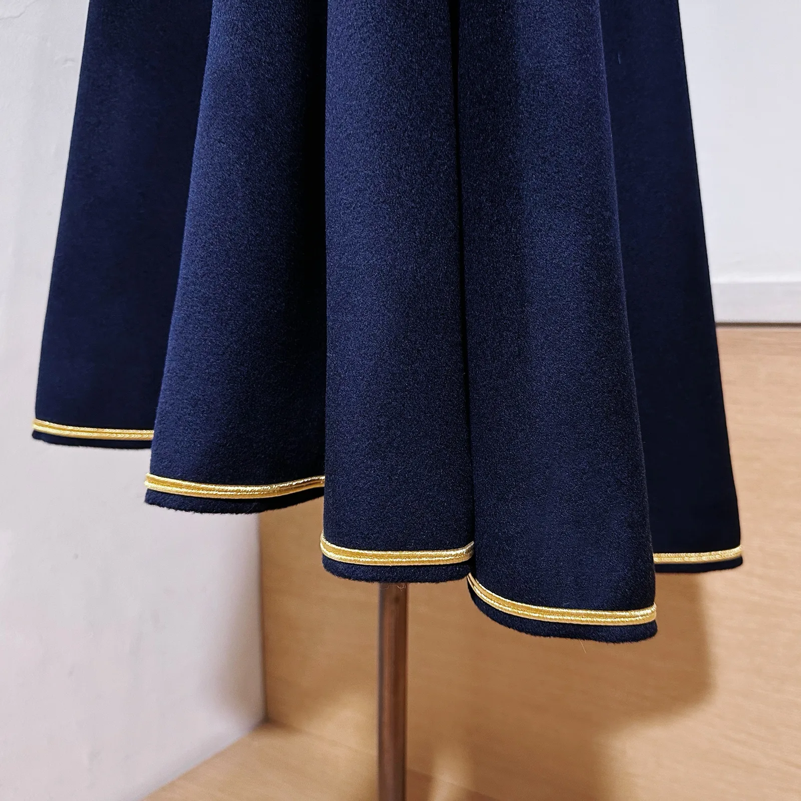 Hem and edge detail on deep navy cavalry cape with gold piping.